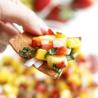Easy mango salsa recipe with strawberries and basil on a tortilla chip