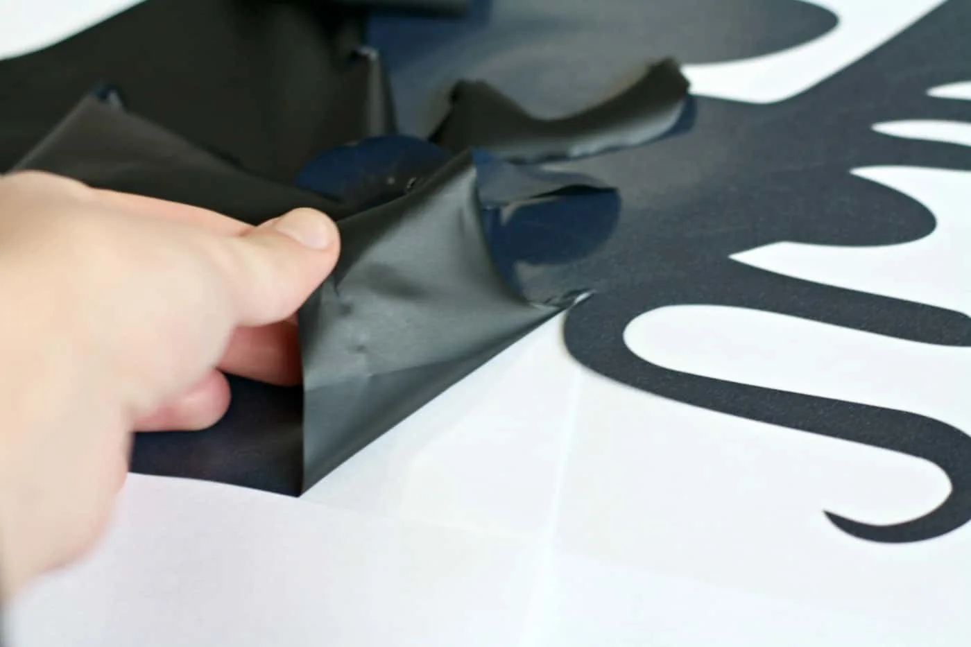 Hand removing excess vinyl from a cut design