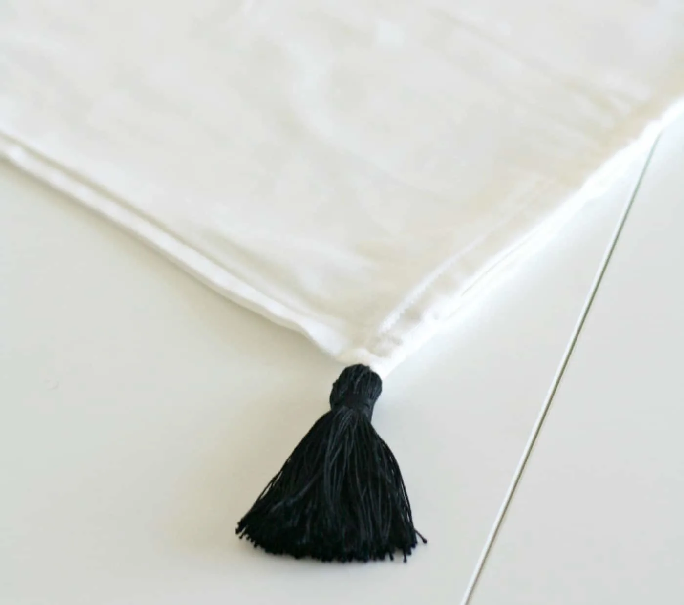 Tassel hand sewn to the corner of a white pillow cover