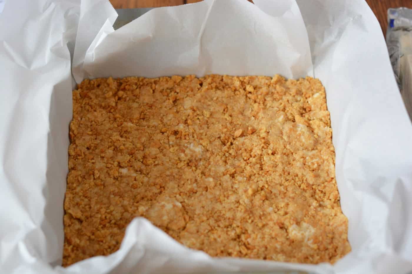 Crust pressed into the square pan lined with parchment paper