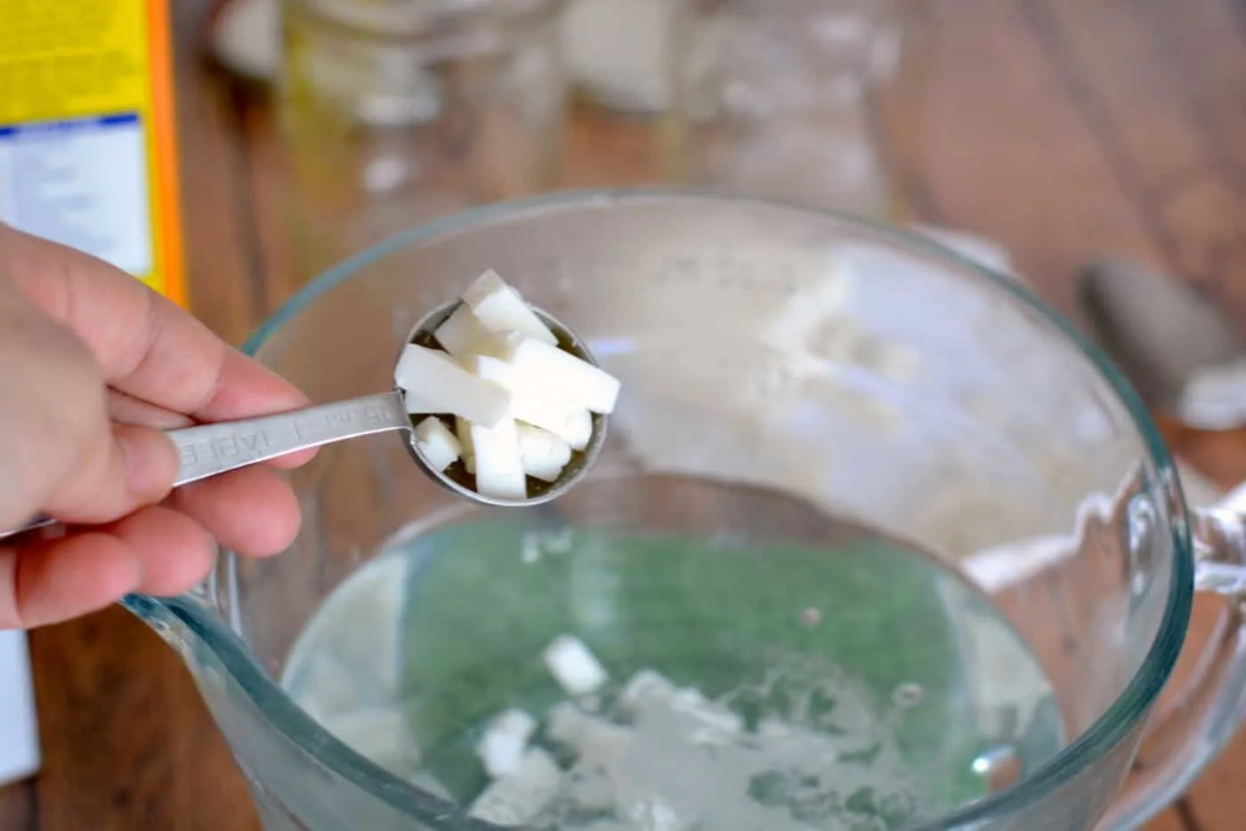 Chunks of castile soap being added to a container of boiling water