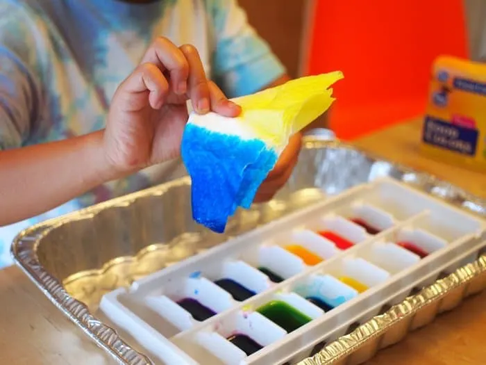 Child's hands dipping a paper towel into the dye