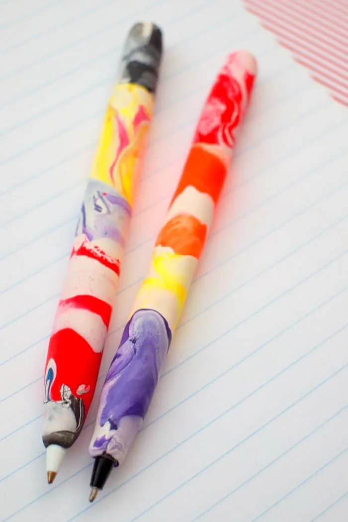 Two polymer clay pens laying a on piece of notebook paper