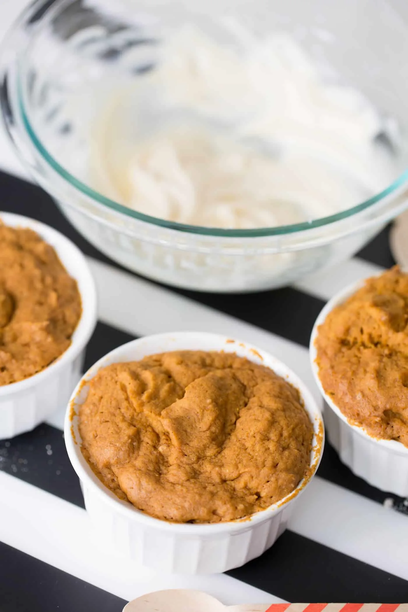 Cooked pumpkin mug cakes with frosting in a glass bowl