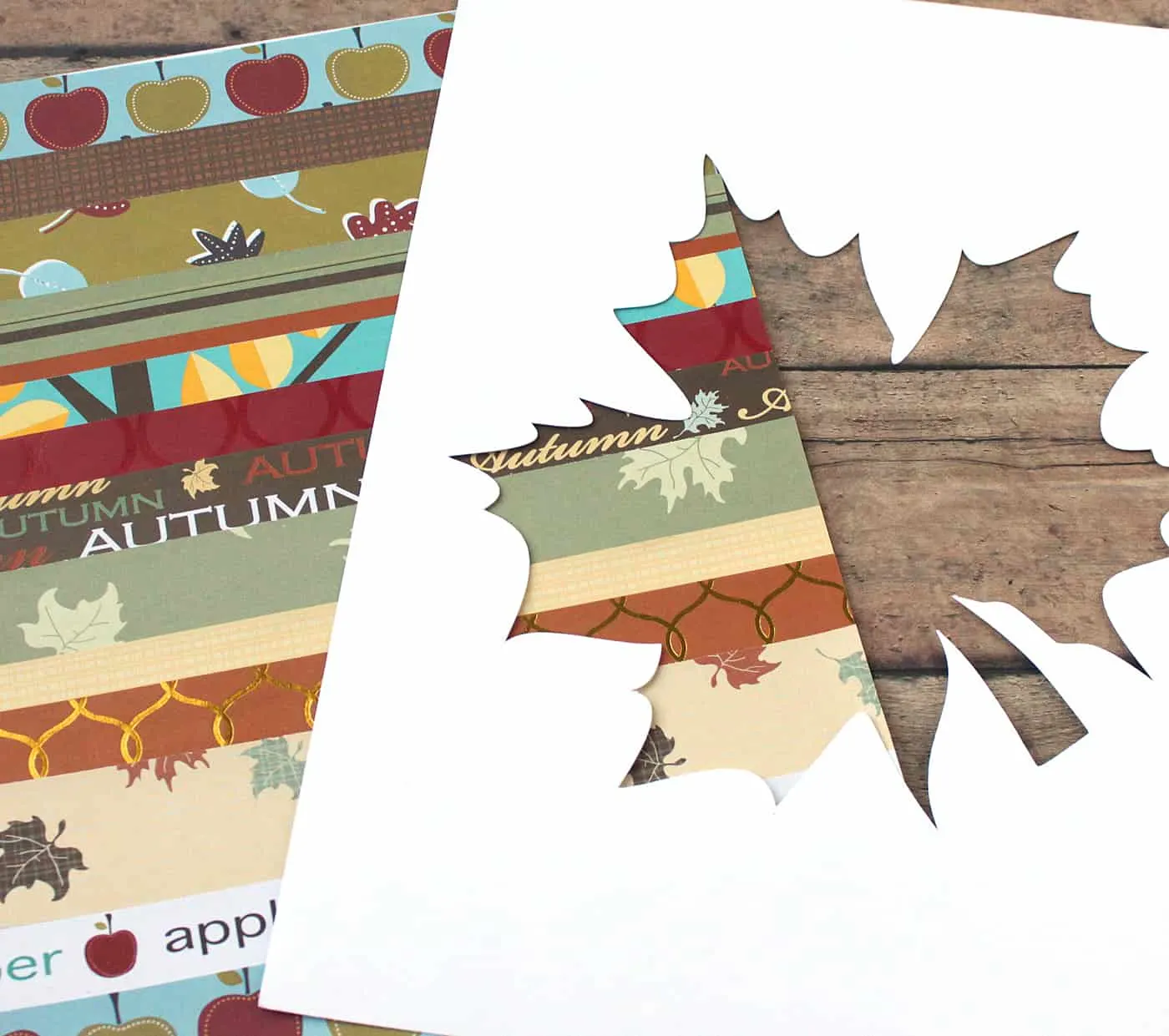 Fall scrapbook paper background and a cardstock piece with a leaf design cut out of it