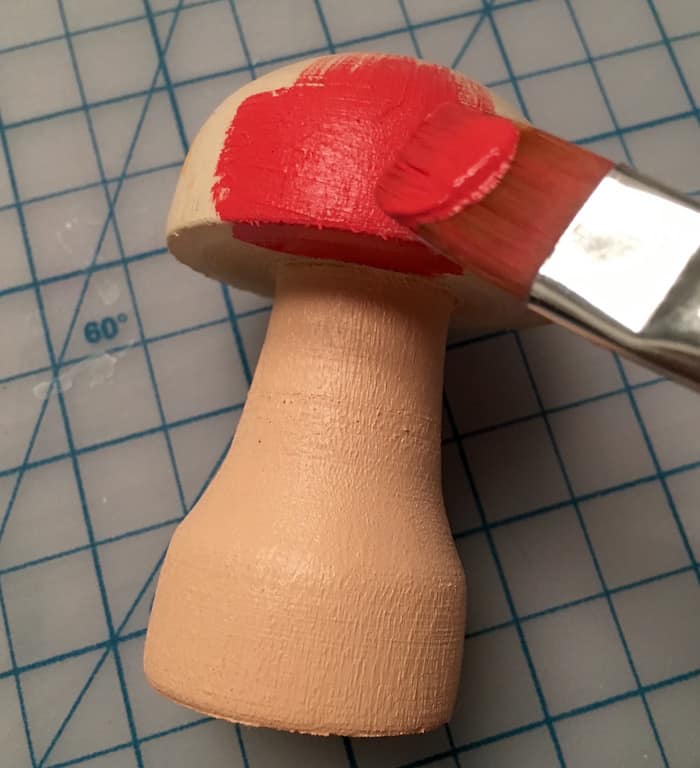 Painting the wood mushroom with red on the cap