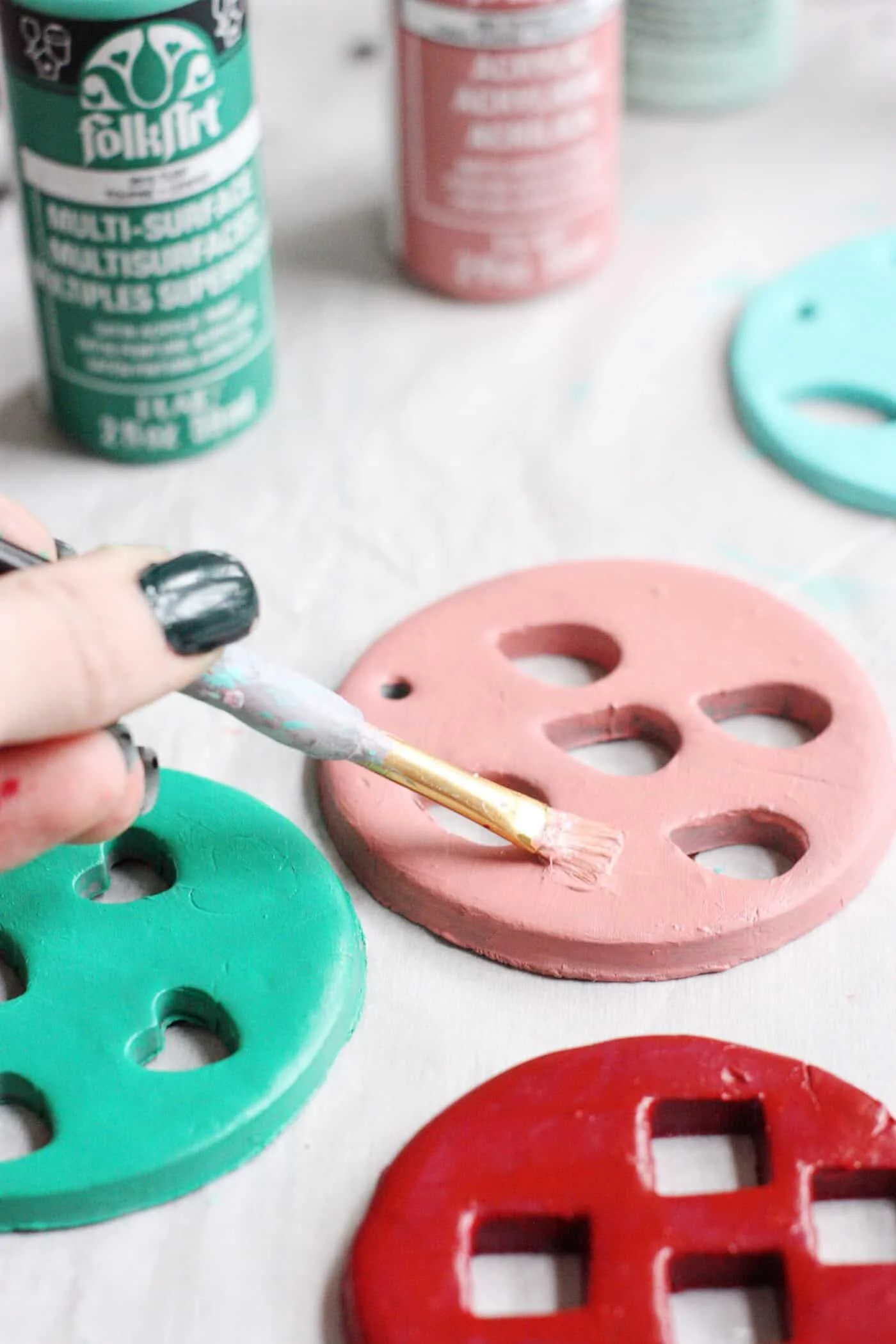 Painting clay Christmas ornaments with various colors of acrylic paint