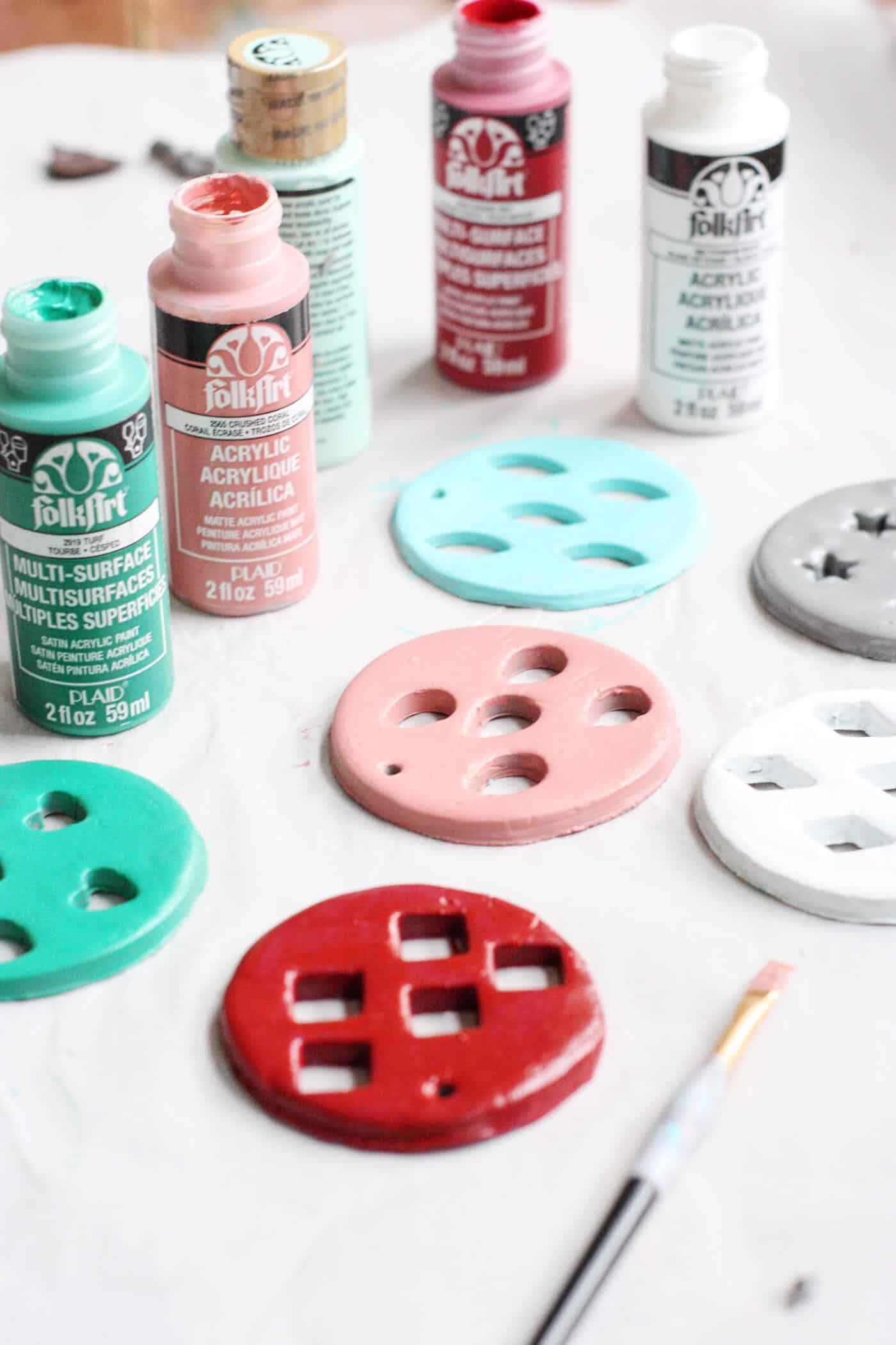 Bottles of acrylic paint and painted clay Christmas ornaments