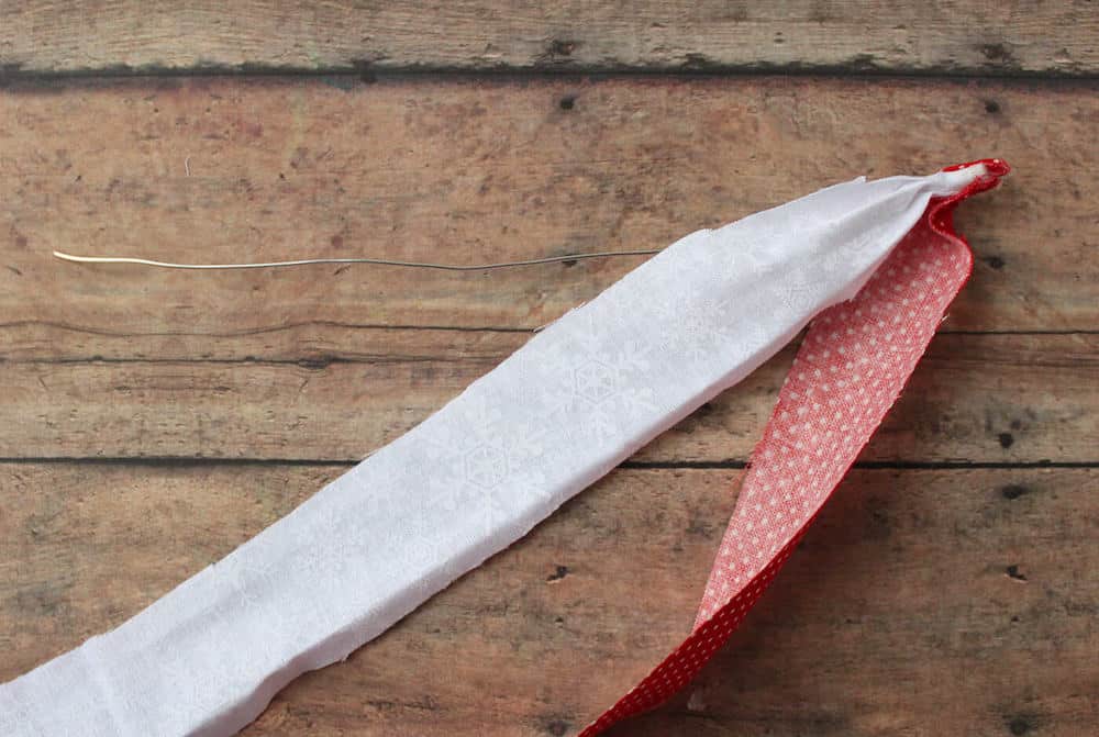 Hot glue the ends of a red and white strip of fabric to one end of the wire