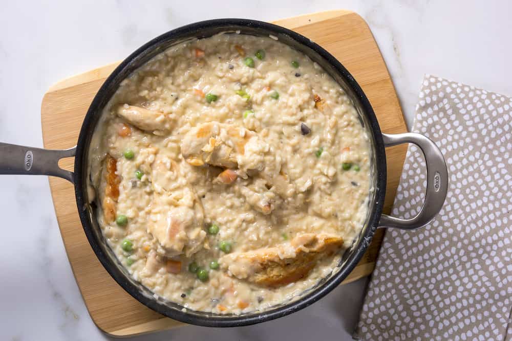 Chicken risotto in a saucepan on a cutting board