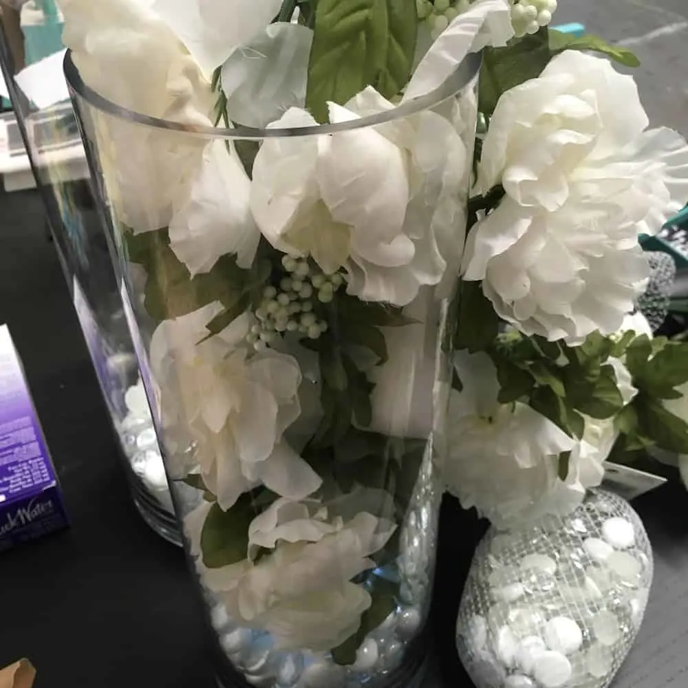 Faux flowers being inserted into the glass vase