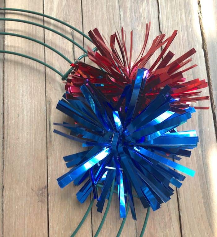 Red and blue metallic pom poms attached to a wire wreath frame