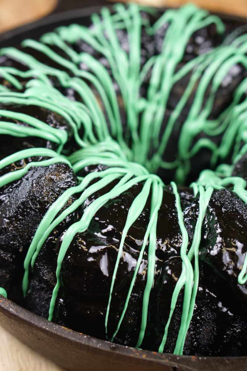 Green icing drizzled over the top of black monkey bread