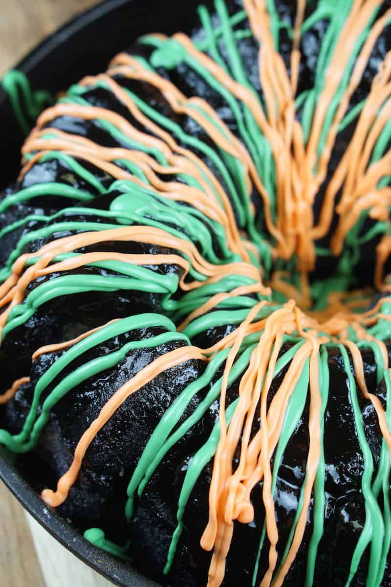 Orange frosting drizzled on top of the green frosting on Halloween puzzle bread