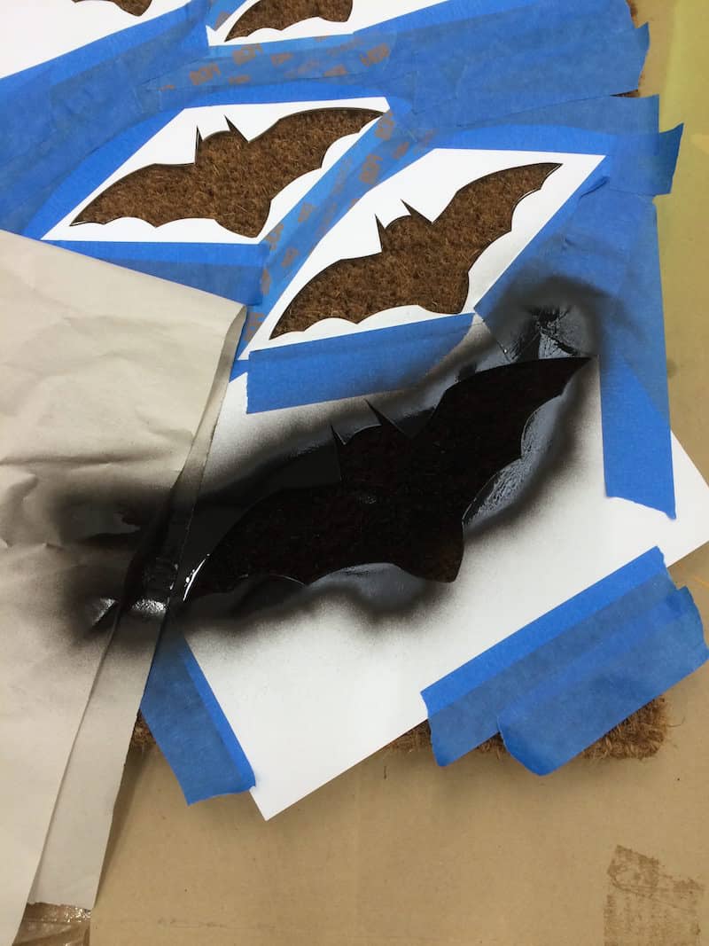Black spray painted bat stencil taped to a door mat