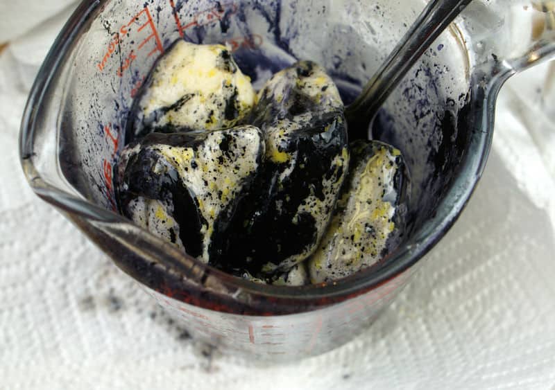 Mixing gel food coloring and butter together in a measuring cup with a spoon