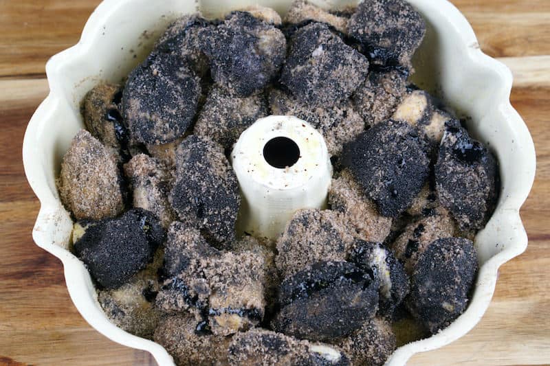 Black pieces of biscuit dipped in sugar in a bundt pan