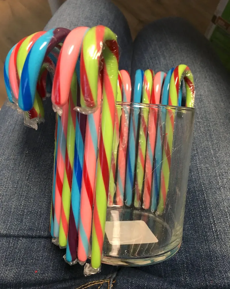 Hot gluing candy canes onto a glass vase