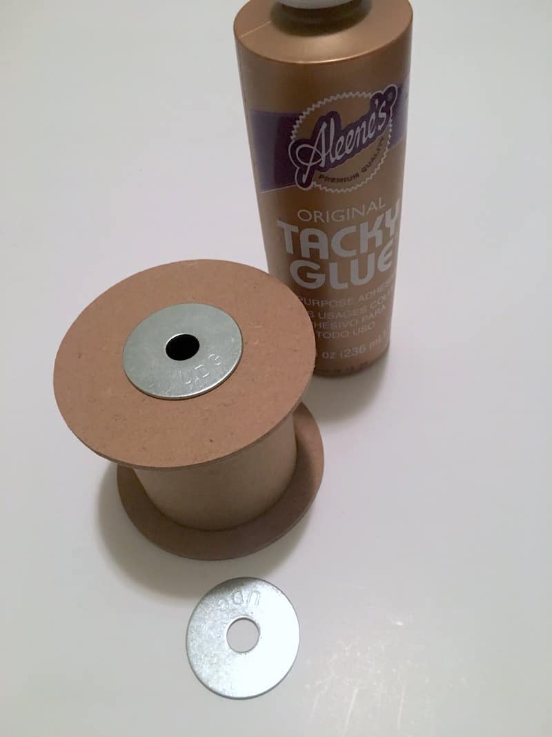 Ribbon spool with a washer on top and a bottle of Aleene's original tacky glue