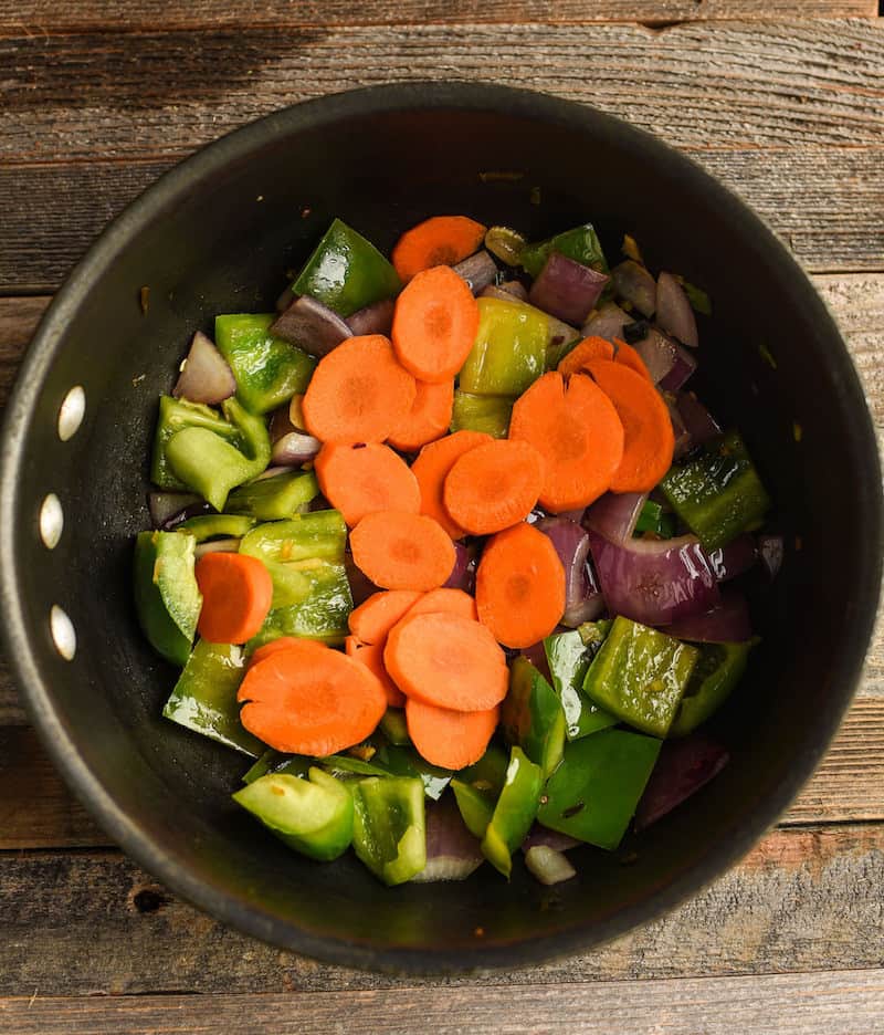 cooking carrots, pepper, and onion in a pan