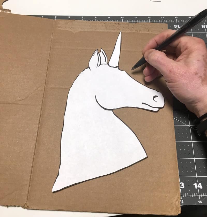 Tracing a unicorn head pattern on a portion of the shoe box with a pen