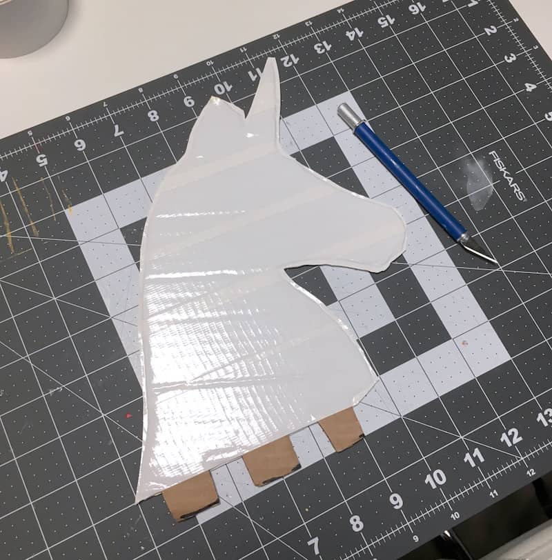 Cut out unicorn head covered in Duck Tape on a cutting mat