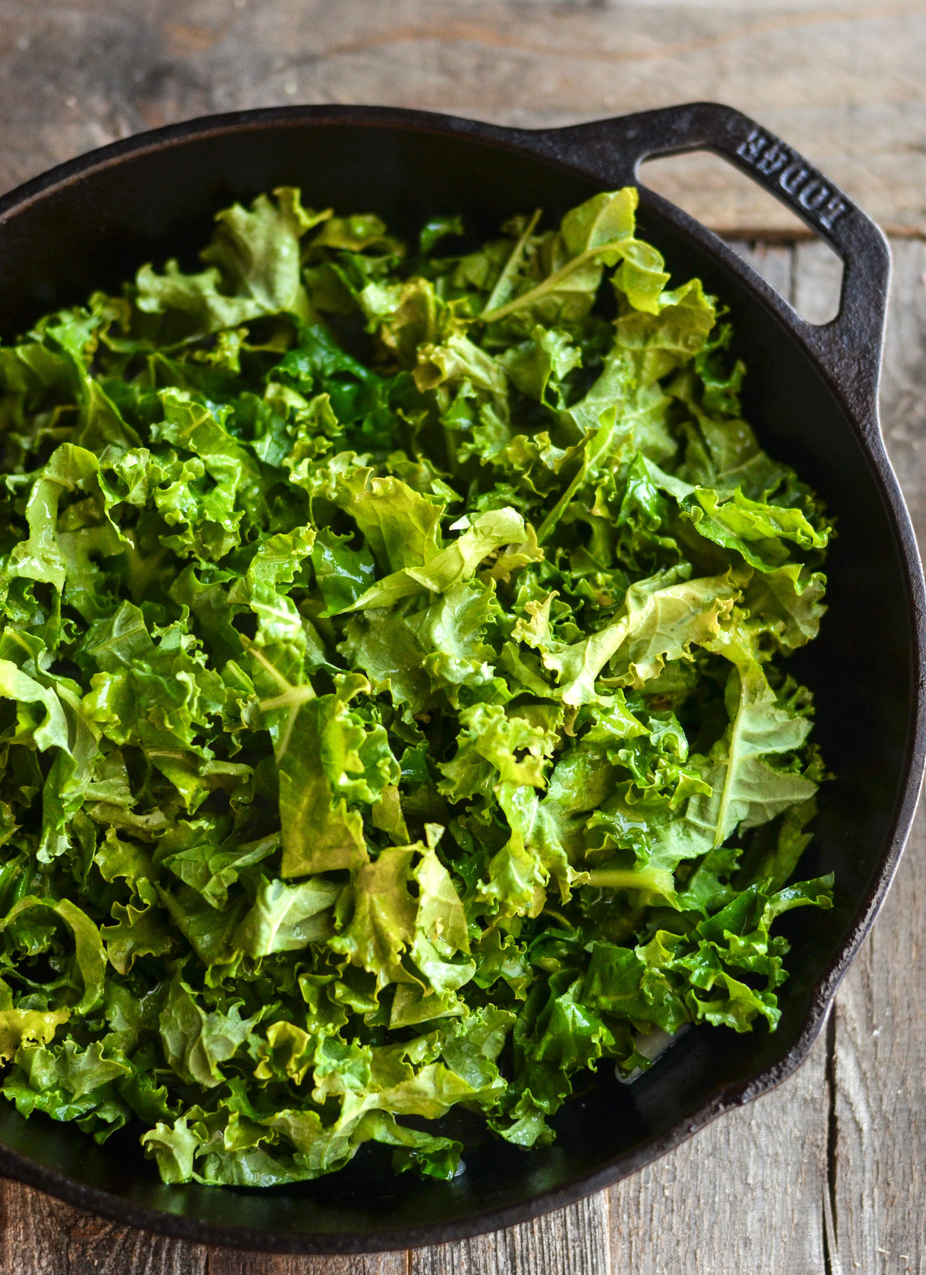 Kale cut into thin strips and added to a cast iron pan