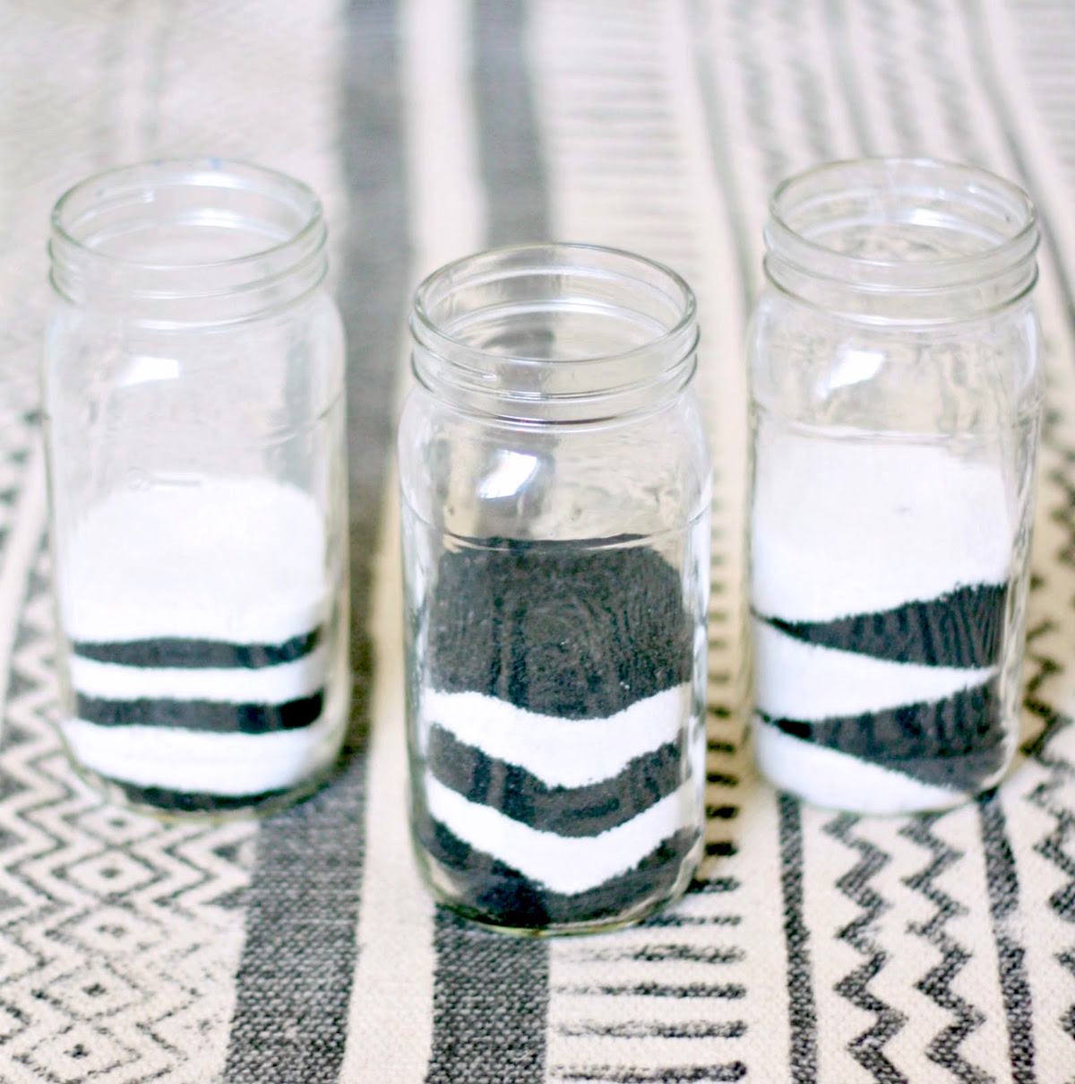 Layers of black and white sand in mason jars