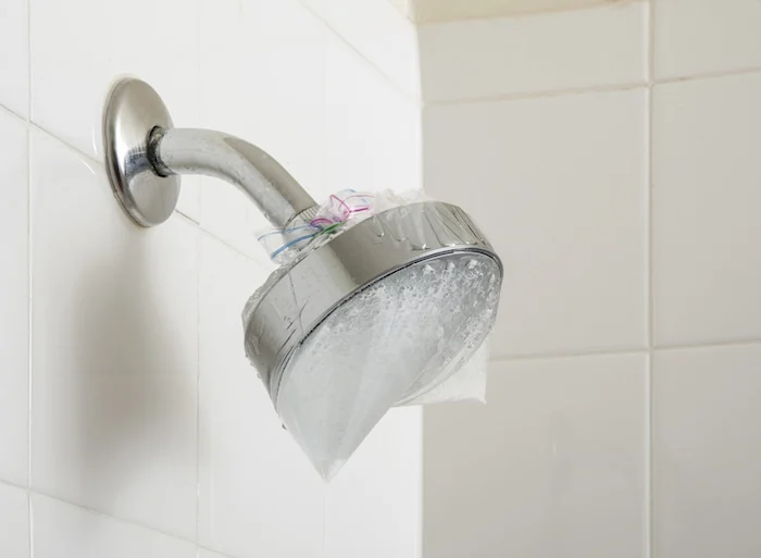 Showerhead soaking in water and vinegar in a plastic bag