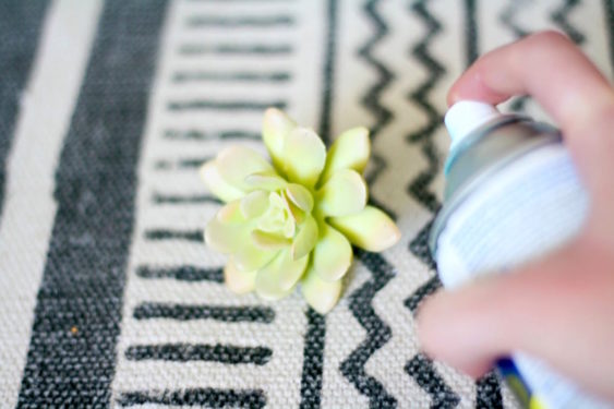 Spray painting a faux succulent with aqua spray paint