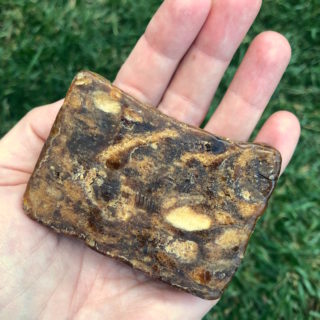 A piece of African black soap in the palm of a womans hand