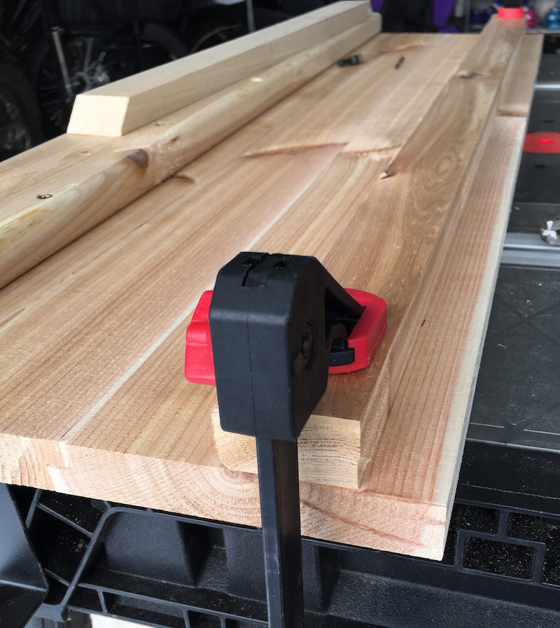 Cedar table planks glued together with a bar clamp
