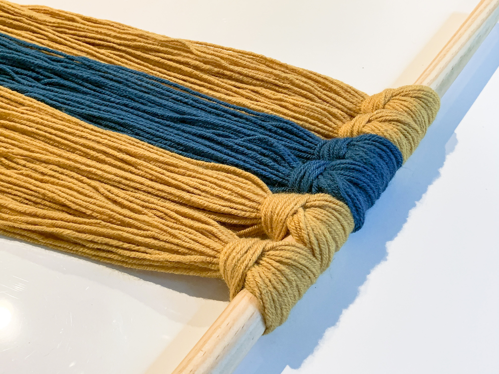 yarn attached to a dowel rod