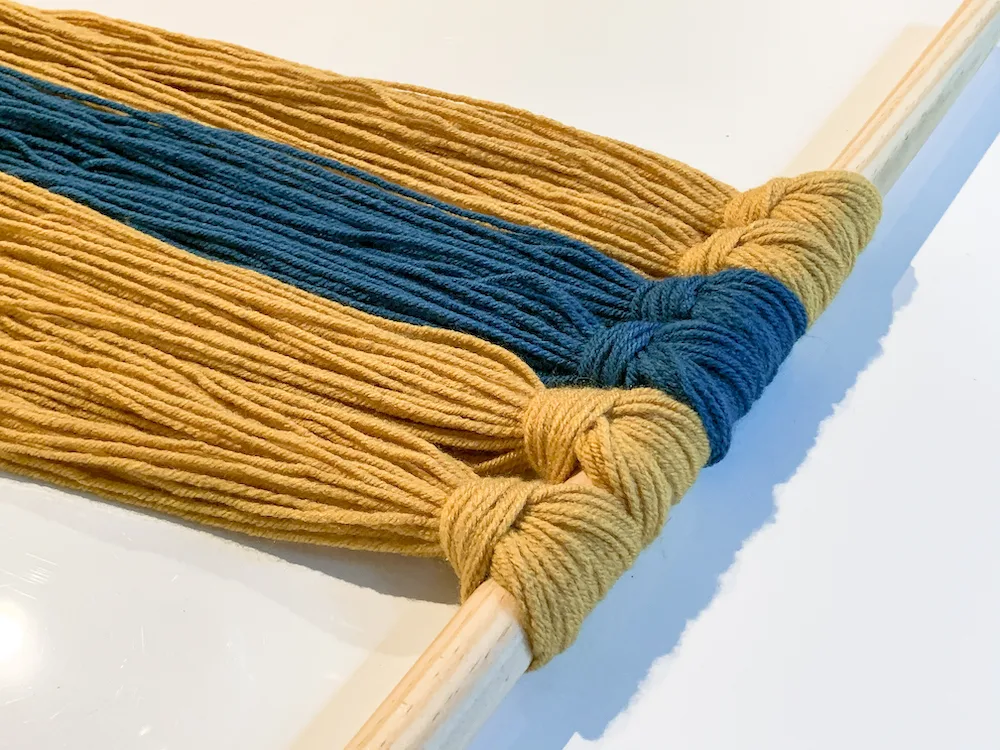 yarn attached to a dowel rod