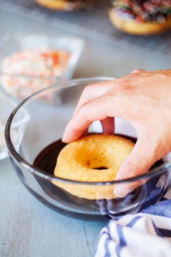 Dipping a baked donut in chocolate frosting