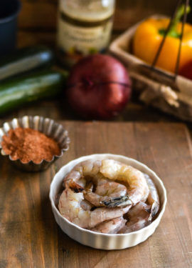 Shrimp in a white ramekin next to a tin of spices