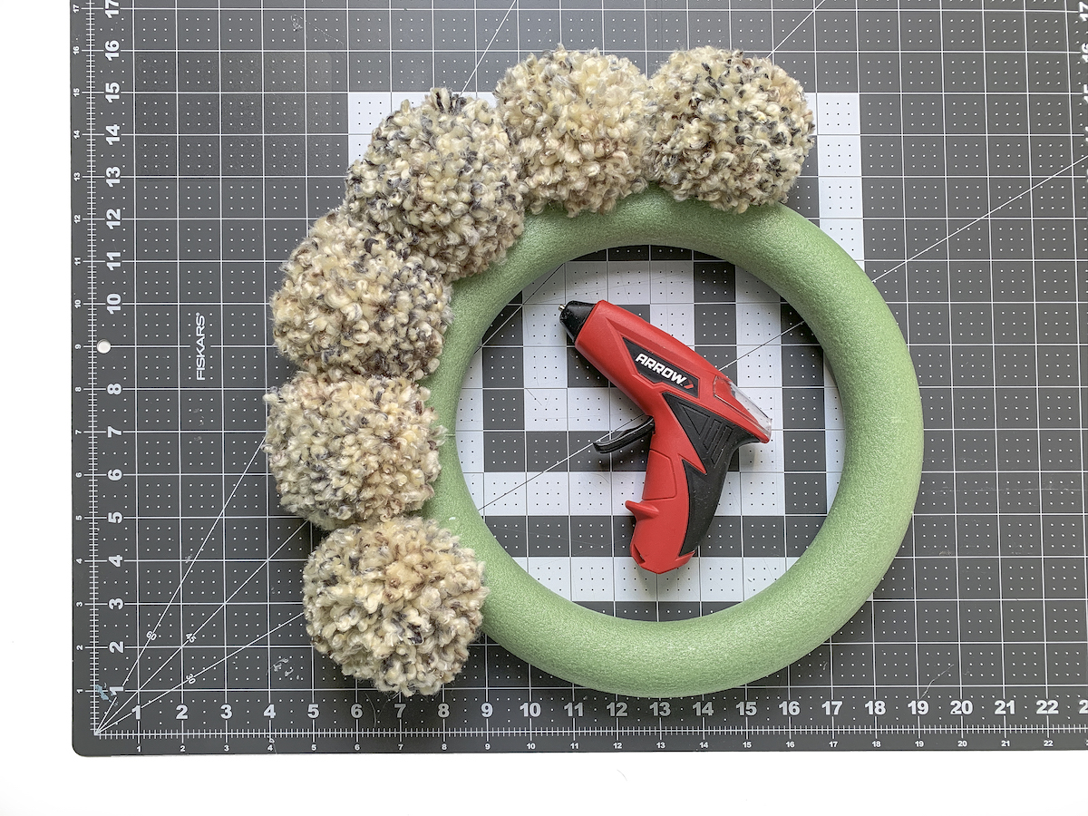 Wreath form with pom poms and a hot glue gun