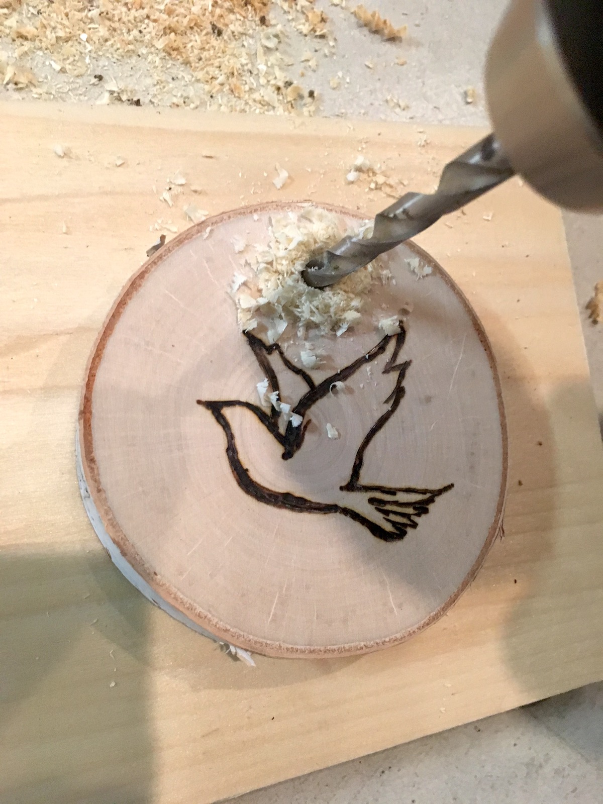 Drilling into a wood slice ornament with a drill