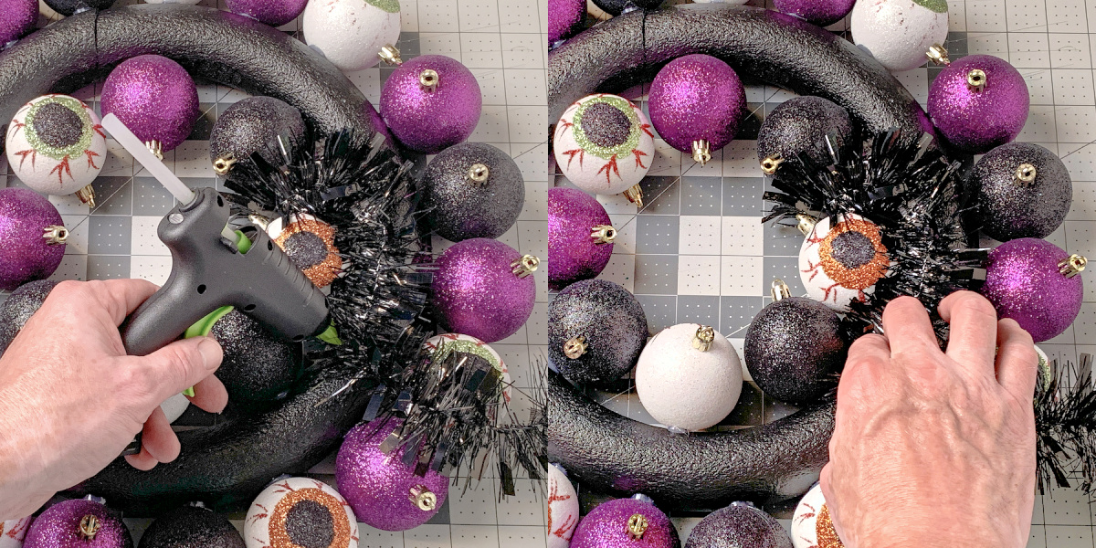 Adding black garland to a wreath form with a hot glue gun