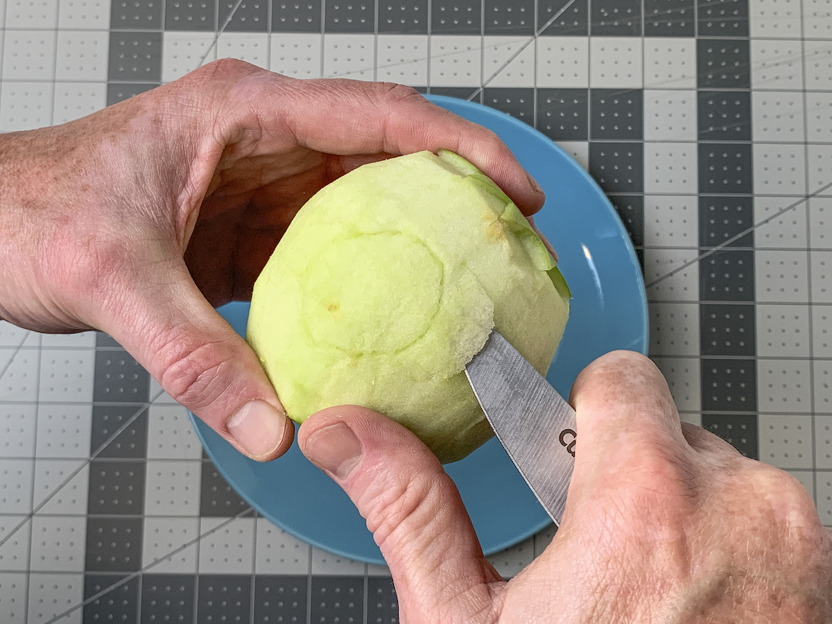 Carving around an ear shape on an apple with a knife