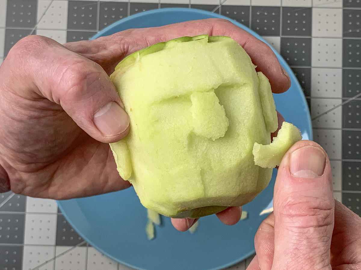 Cutting under the nose of a shrunken head apple using a knife