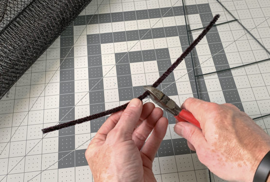 Hand clipping a pipe cleaner in half with wire cutters