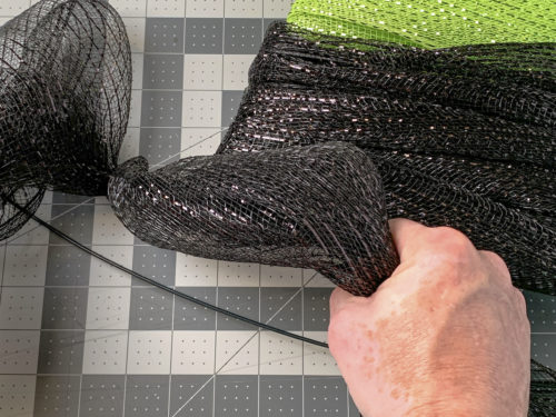 Hand grabbing black mesh to bunch it