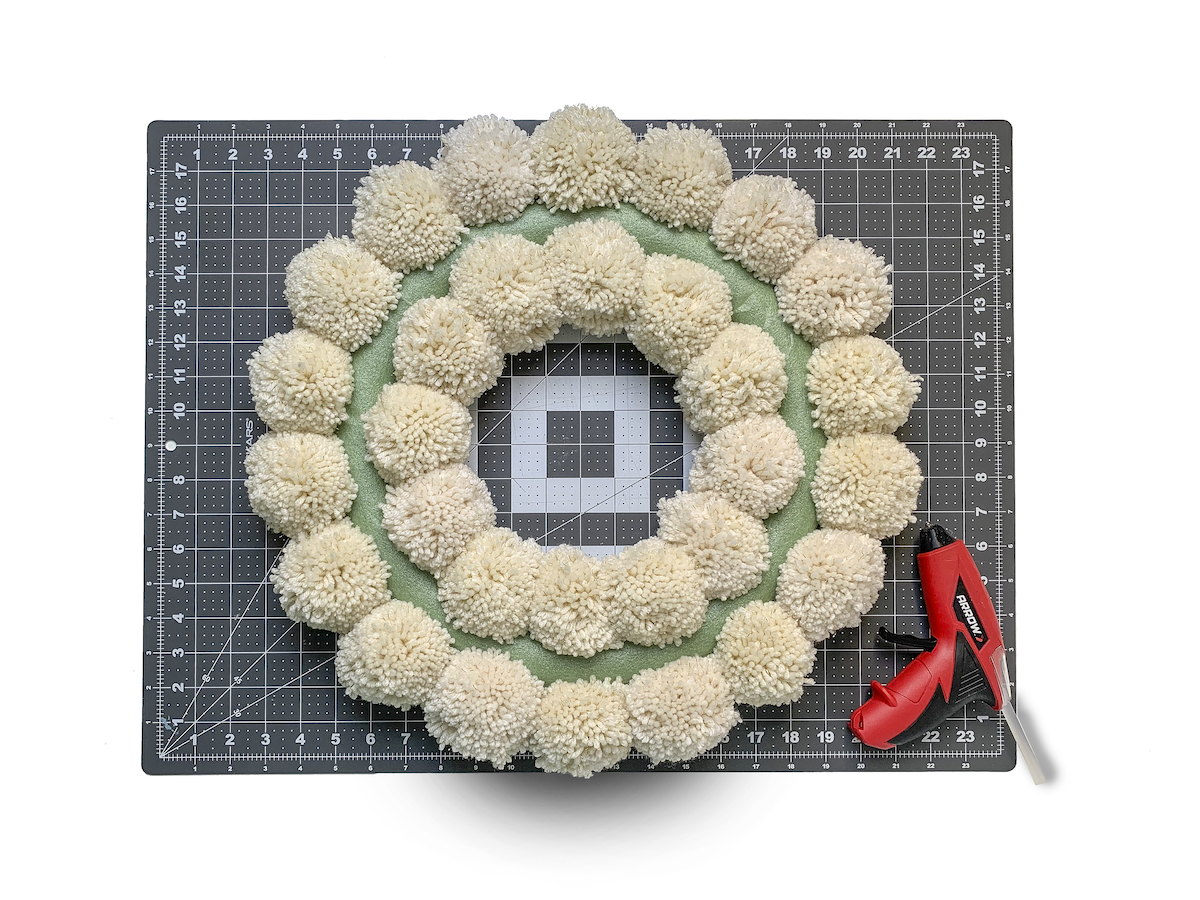 Second ring of pom poms around a wreath form