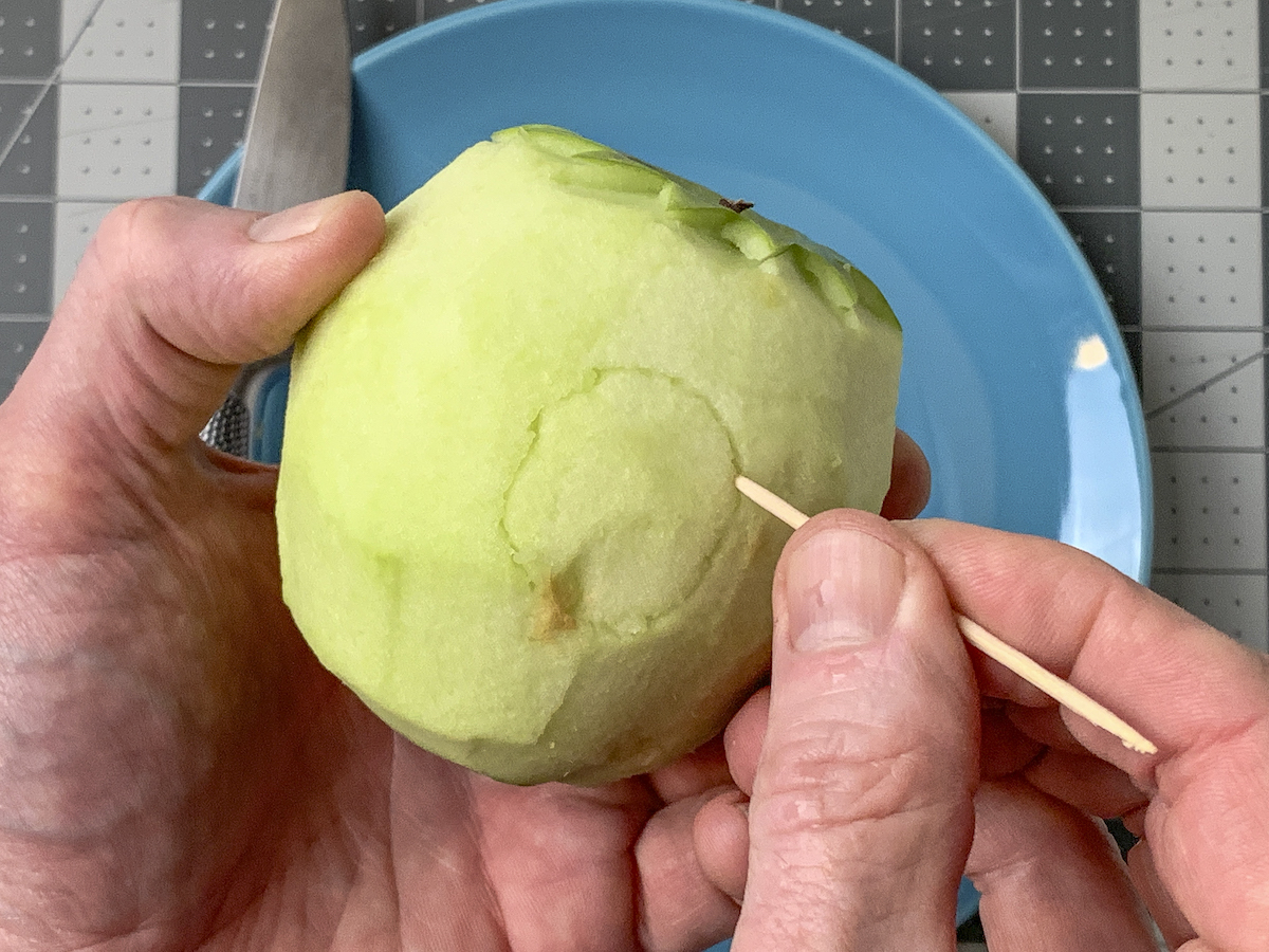 Tracing an ear shape on an apple with a toothpick