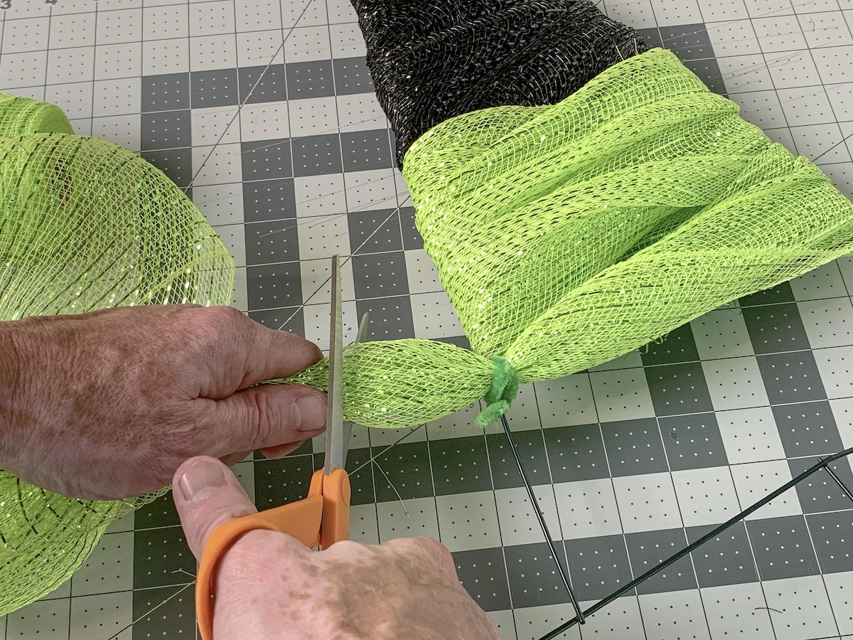 Trimming the green mesh with scissors