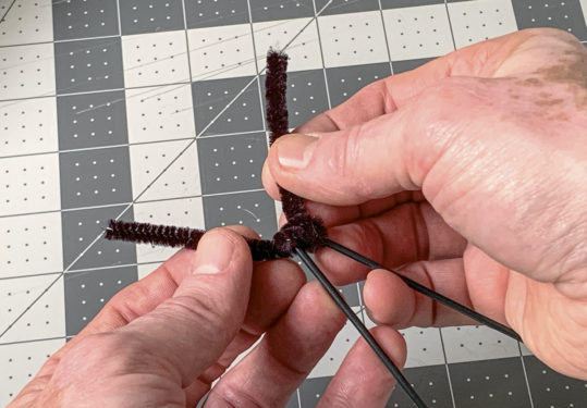 Wrapping a pipe cleaner around the top of the wreath form