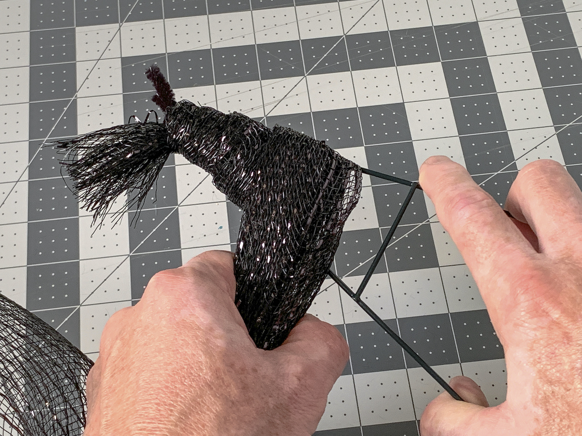Wrapping deco mesh around the top of the witch hat wreath form