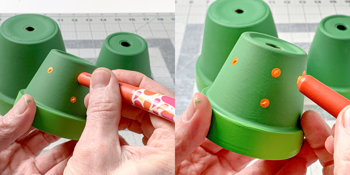 Adding painted dots to a green clay pot with the end of a paint brush