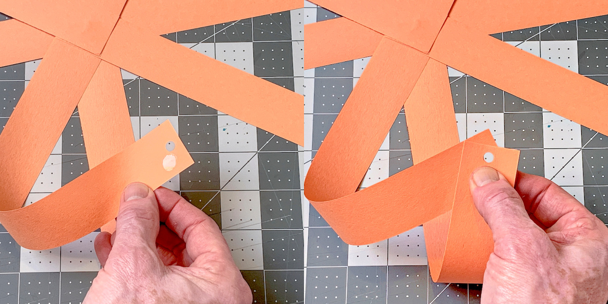 Attaching two strips of paper together with a glue dot and matching the holes